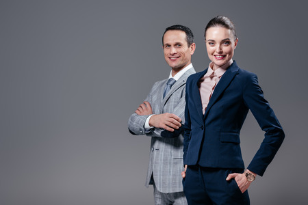 Successful adult business colleagues looking at camera isolated on grey backgroundの写真素材