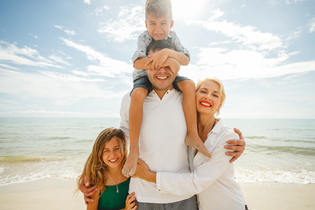 Happy family on vacation standing together in front of oceanの写真素材