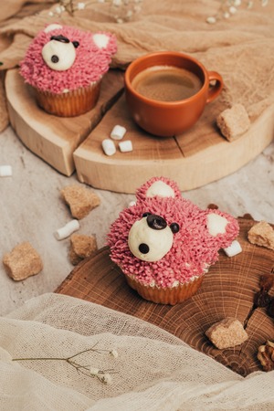 close-up view of delicious sweet cupcakes in shape of bears and cup of coffee on table
