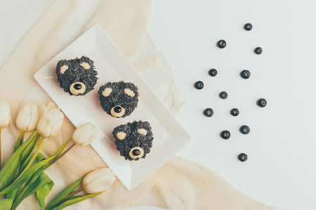 Top view of gourmet cupcakes in shape of bears, fresh blueberries and tulip flowersの写真素材