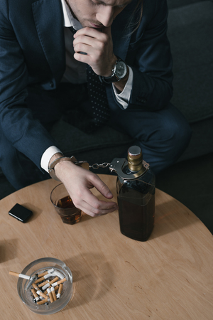 alcohol addicted businessman with glass and bottle of whiskeyの写真素材