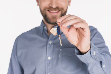 Cropped shot of smiling man showing key from new house in hand isolated on white backgroundの写真素材