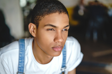 Young attractive African American boy looking away while sitting in cafeの写真素材