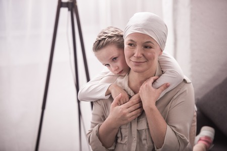 Cute little child hugging sick grandmother in kerchiefの写真素材