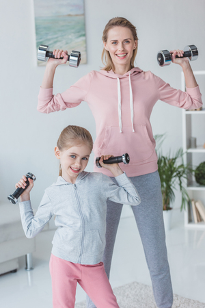 healthy mother and daughter working out with dumbbells at homeの写真素材