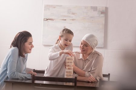 happy family of three generations playing with wooden blocks together, cancer concept