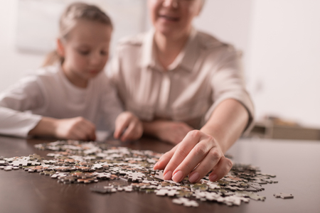 Close-up view of grandmother and granddaughter playing with jigsaw puzzle together, cancer conceptの写真素材