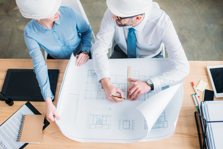 High angle view of experienced architects working with building plan at officeの写真素材