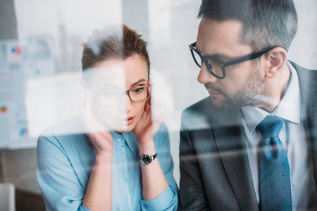 Young business partners talking behind glassの写真素材