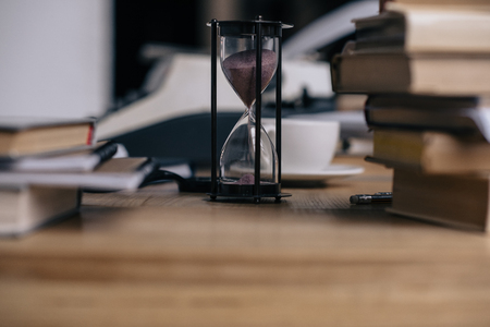 Close-up shot of hourglass and stacked booksの写真素材