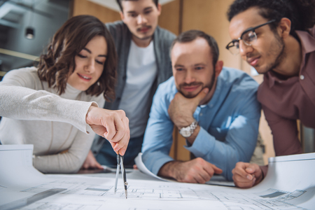 close-up shot of group of architects drawing building plan together at officeの写真素材