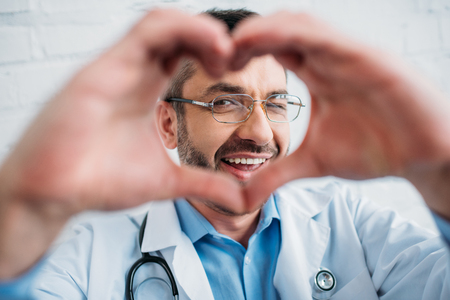 Happy handsome doctor showing heart sign with handsの写真素材