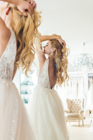 Beautiful tender bride by mirror in wedding fashion shopの写真素材