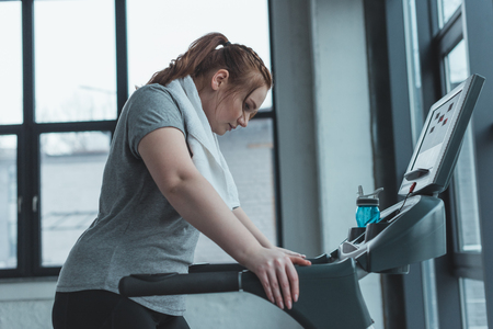 Obese girl resting on treadmill in gymの写真素材