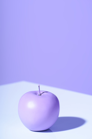 Purple apple on violet background with copy spaceの写真素材