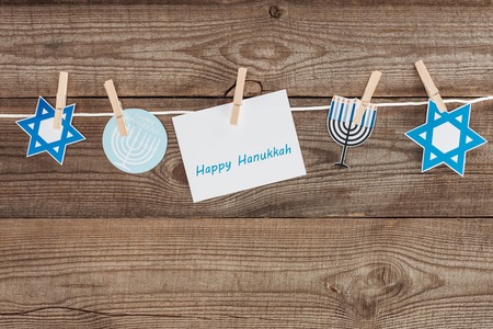 top view of happy hannukah card and holiday paper signs pegged on rope on wooden tabletop, hannukah conceptの写真素材