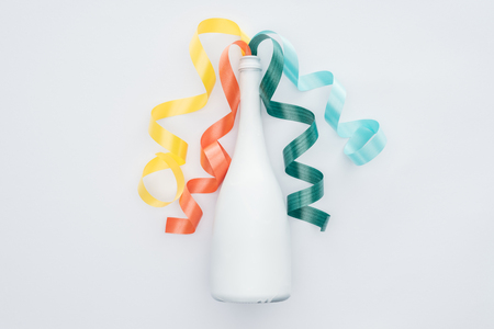 top view of colorful ribbons and white bottle isolated on whiteの写真素材