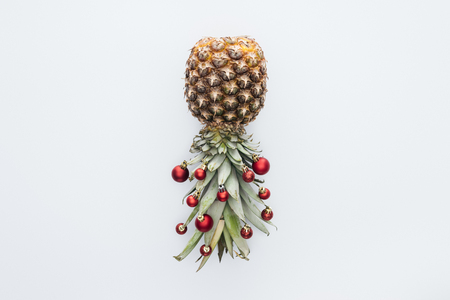 Top view of red Christmas balls on fresh pineapple isolated on white backgroundの写真素材