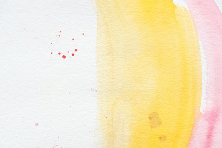 Pink and yellow paint strokes with red splatters on white paper backgroundの写真素材