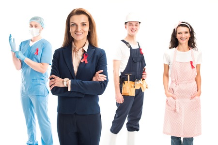 smiling businesswoman, doctor, worker and housewife standing with red ribbons isolated on white, world aids day conceptの写真素材