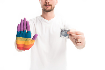 cropped image of homosexual man with hand painted in rainbow holding condom isolated on white, world aids day conceptの写真素材