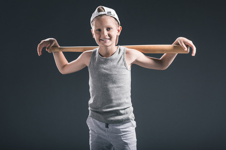 portrait of preteen boy in cap with baseball bat on grey backgroundの写真素材
