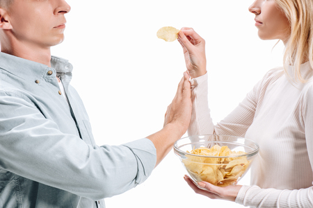 cropped image of man rejecting unhealthy potato chips from woman isolated on whiteの写真素材
