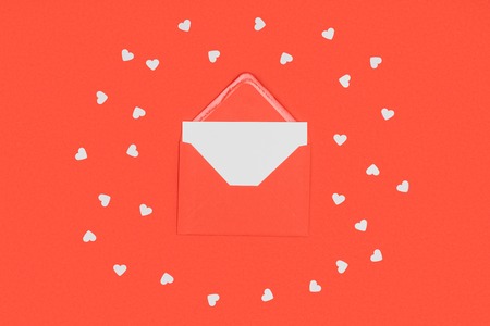 close-up view of red envelope with white card and small hearts isolated on red