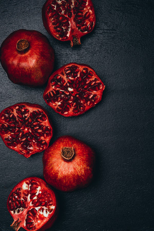 top view of ripe pomegranates arrangement on black surfaceの写真素材