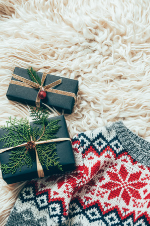 Top view of wrapped Christmas presents and winter sweater on woolen backdropの写真素材