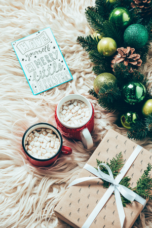 top view of christmas wreath, cups of cocoa drinks with marshmallows and postcard with have yourself marry little christmas lettering on woolen backdropの写真素材