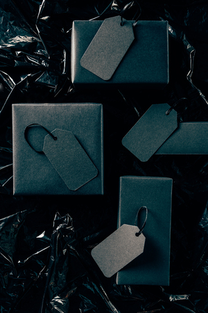 flat lay with black boxes with blank price tags on black wrapping paper backdrop, black friday...