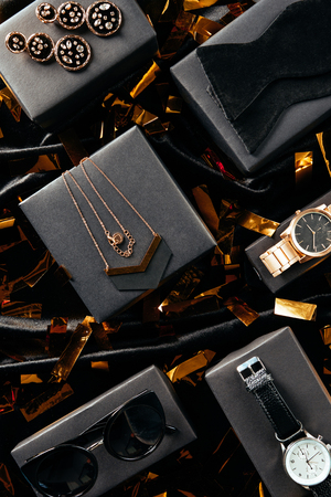 flat lay with feminine shoes, purse and jewelry on black background with golden confettiの写真素材