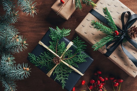 top view of christmas gift boxes with fir branches and decorative berries on wooden background