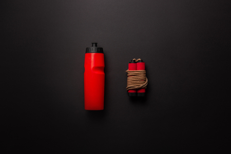Flat lay with red sport bottle and jump rope isolated on black, minimalist conceptの写真素材