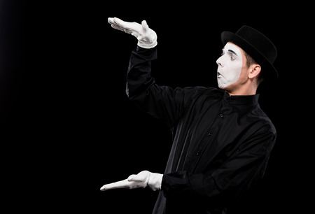 surprised mime showing size of something isolated on blackの写真素材