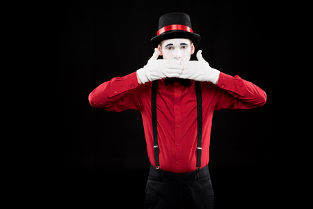 mime covering mouth with hands isolated on blackの写真素材