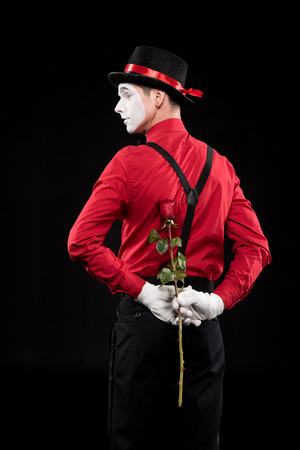 mime hiding rose behind back isolated on blackの写真素材