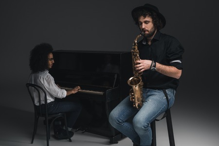 man playing saxophone while his partner playing piano blurred on backgroundの写真素材