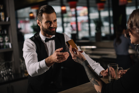 visitor giving credit card to bartender to pay for drinks