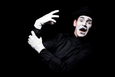 scared mime with hand monster looking at camera isolated on blackの写真素材