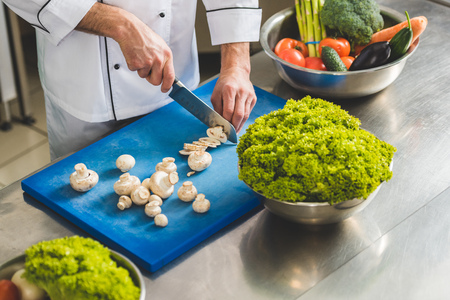 cropped image of chef cutting mushrooms at restaurant kitchenの写真素材