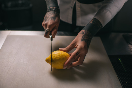 cropped image of tattooed girl cutting lemon for drinksの写真素材