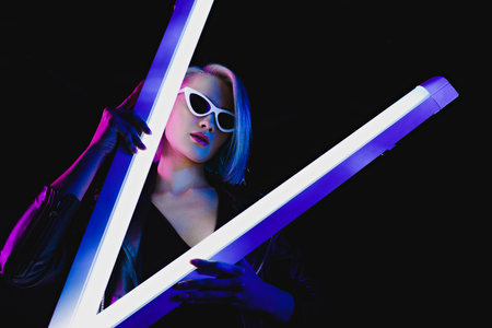beautiful stylish model in sunglasses posing with two ultraviolet lamps for fashion shoot, isolated...