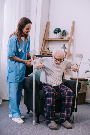 Nurse holding male patient with crutchesの写真素材