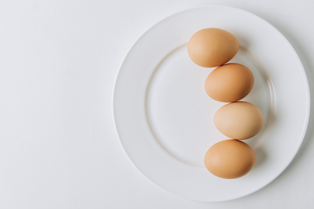 brown eggs laying on white plate on white backgroundの写真素材
