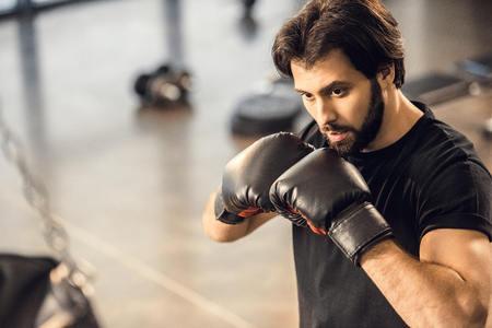 handsome focused young man in boxing gloves exercising in sports centerの写真素材