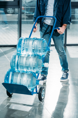Delivery man pushing cart with water bottlesの写真素材