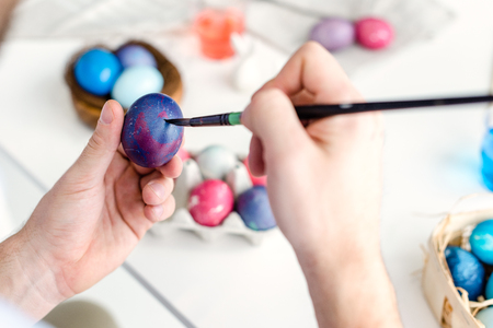 Man coloring Easter eggs with painting brushの写真素材