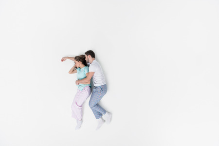 top view of couple in pajamas embracing and sleeping together isolated on whiteの写真素材
